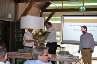 Frank de Miranda ontvangt bloemen als dank voor zijn inzet voor GeoBusiness van de voorzitter